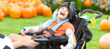 Child in wheelchair with pumpkins in background