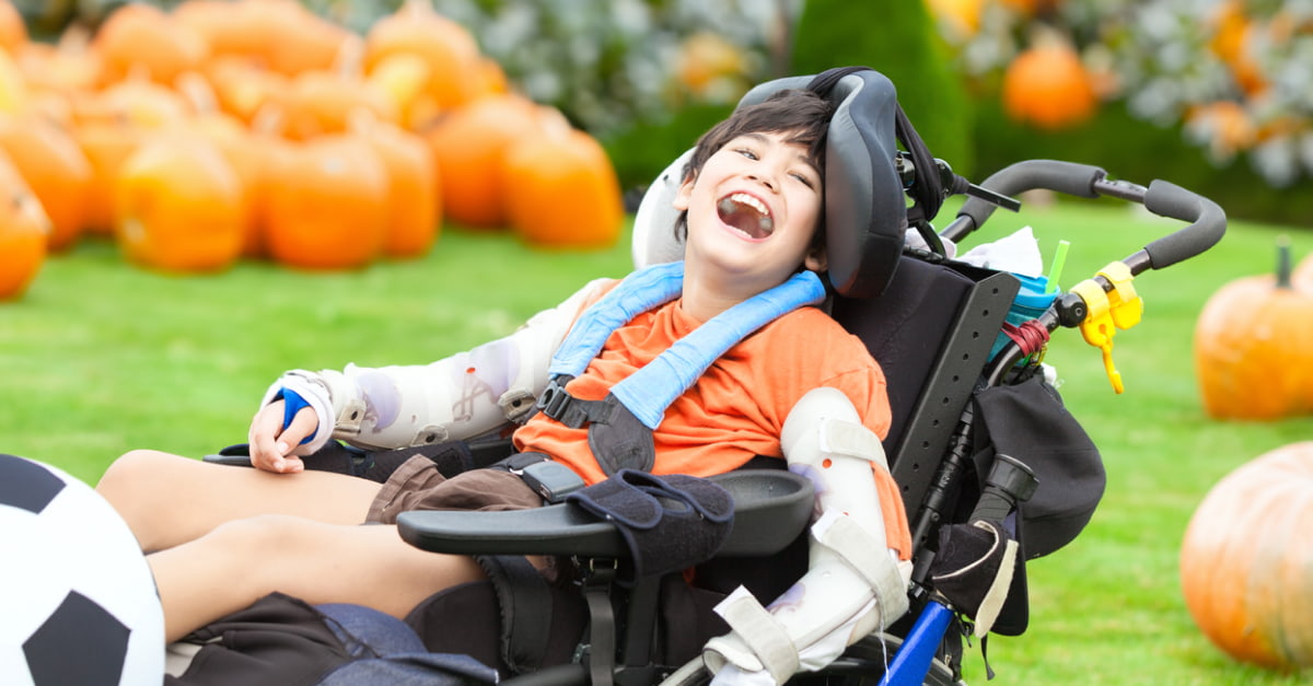 Child in wheelchair with pumpkins in background
