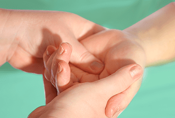 Image of 2 sets of hands. One set of hands in using a massage therapy technique on the other set of hands.