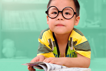 Image of a child wearing glasses and reading a book.