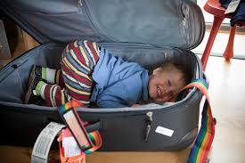 Image of a child in a suitcase that is laughing.