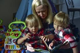Image of a caregiver with children reading a book.