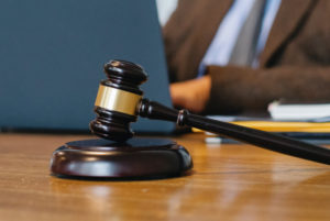 A gavel and block on a desk with an Erb's palsy lawyer working on a laptop in the background.