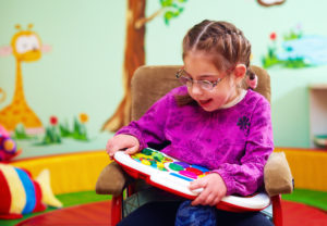 A girl in a wheelchair plays with a developmental toy.