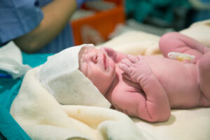 A newborn baby crying on top of a blanket.