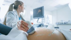 A doctor performs an ultrasound on a pregnant woman.