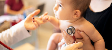 Doctor holds stethoscope to baby's chest