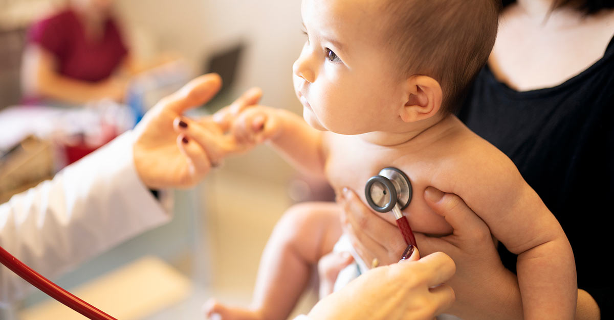 Doctor holds stethoscope to baby's chest