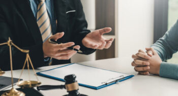 A birth injury lawyer discussing a case with a client at a desk, with a gavel and scales of justice nearby.