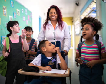 A teacher and students talk and laugh in a cerebral palsy special education setting.