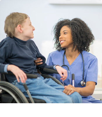 A cerebral palsy treatment facility doctor and patient in a wheelchair talk and laugh together.