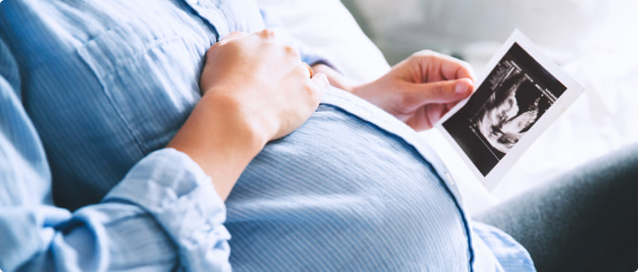 A pregnant woman holding an ultrasound picture. 