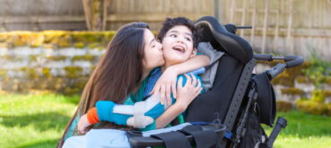 Caregiver embraces child with cerebral palsy