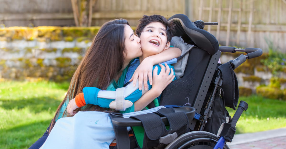 Caregiver embraces child with cerebral palsy