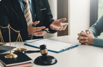 A lawyer discussing a case with a client at a desk, with a gavel, scales of justice, and legal documents nearby.
