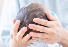 Close-up of a delivery team doctor gently holding a newborn's head.