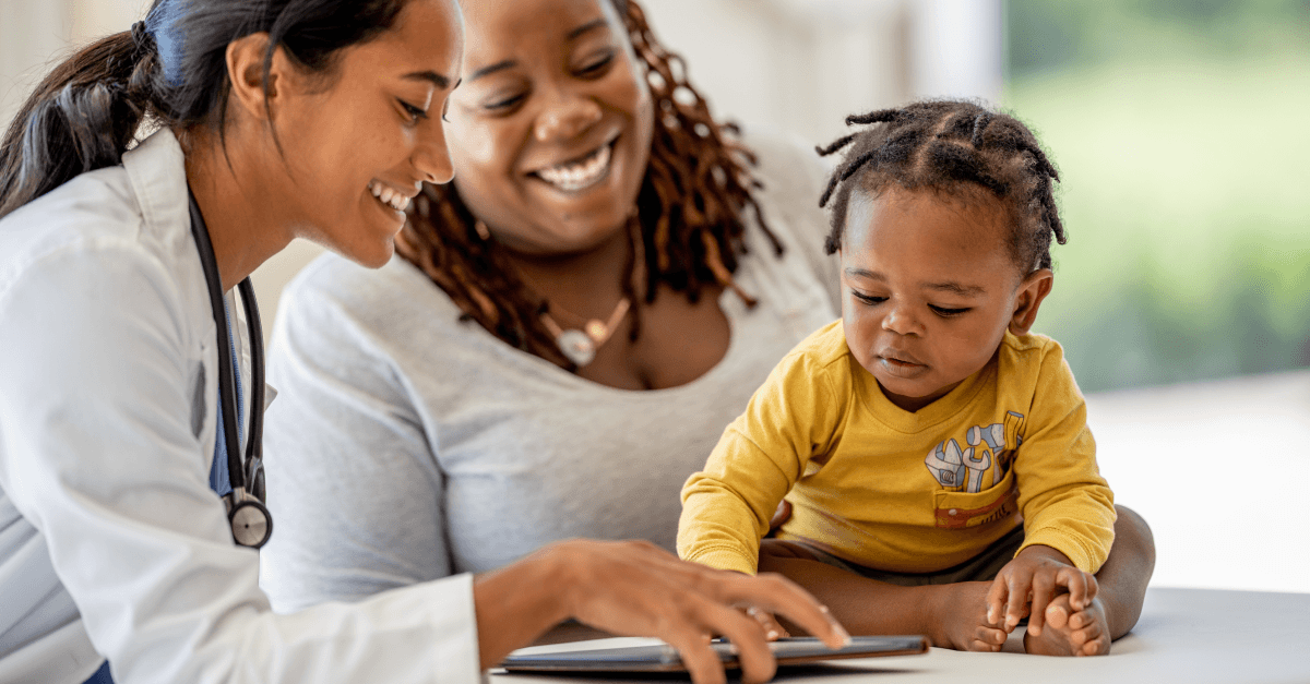 A doctor, parent, and young child look at a tablet during a medical appointment.