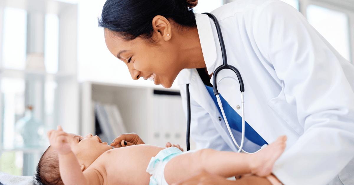 A doctor smiles while examining a baby during a medical checkup.