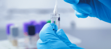 Gloved hands prepare a sample for genetic testing in a laboratory.